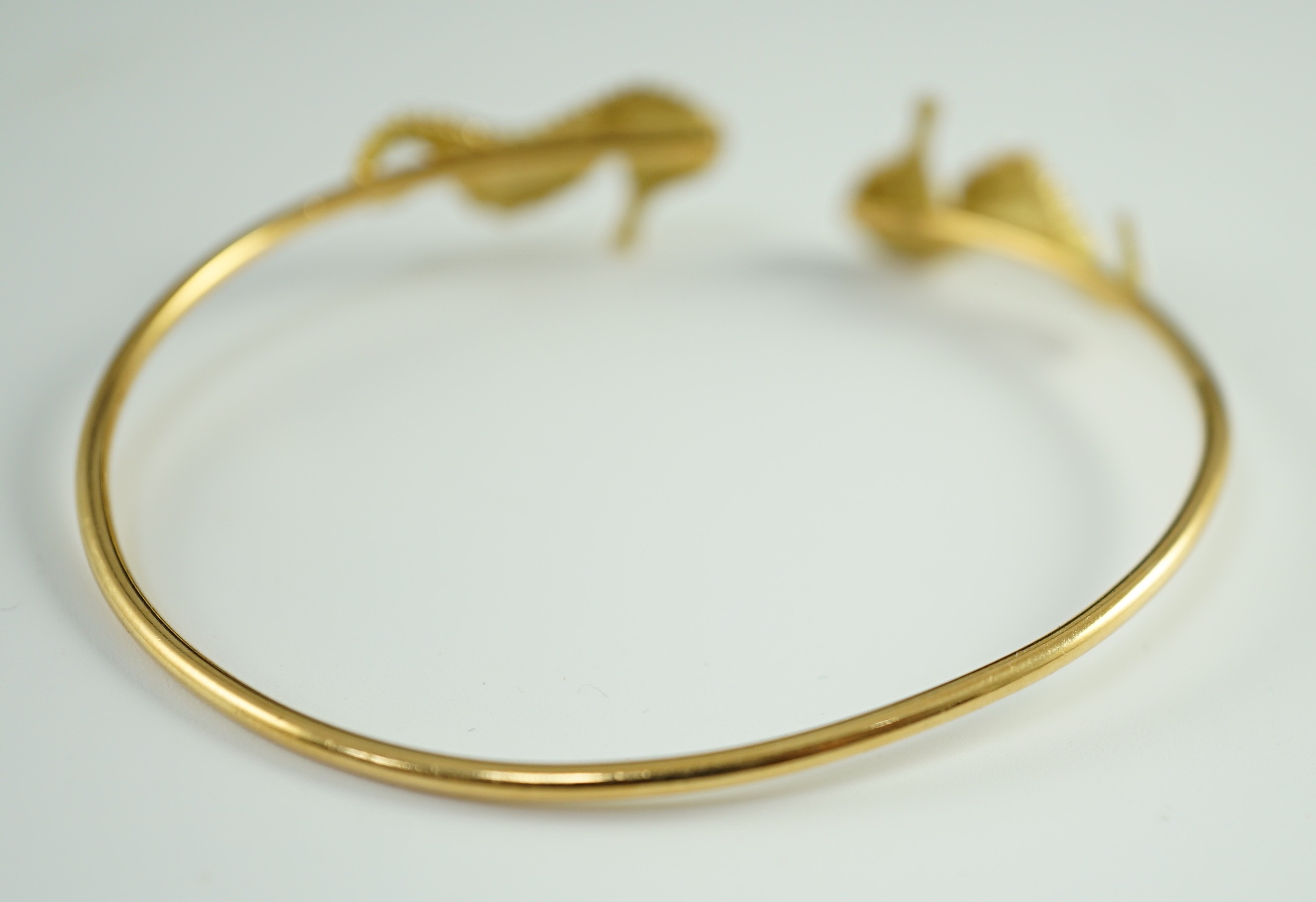 A modern gold and diamond chip set open work bangle, each terminal modelled as a seahorse with diamond chip eye